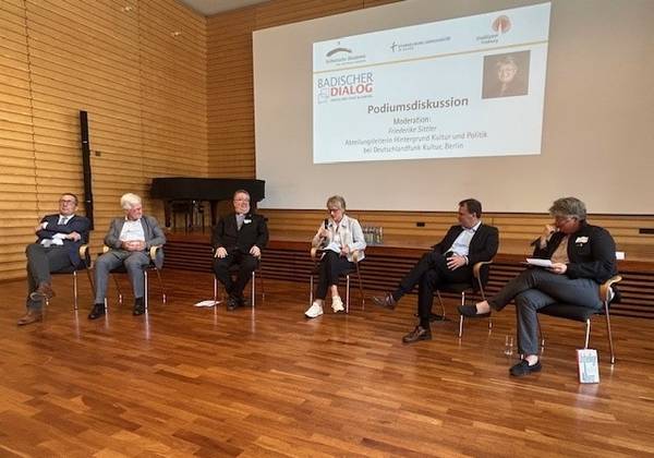 Fünf Personen sitzen diskutierend im Halbkreis in der Aula