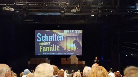 Quelle: Katholische Akademie der Erzdiözese Freiburg Publikum vor Leinwand mit der Aufschrift "Schatten meiner Familie"